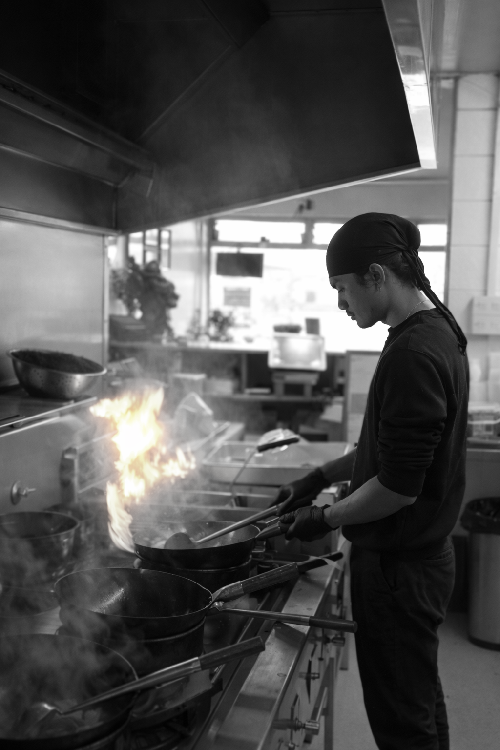 Chef at the wok with dramatic flames shooting upward