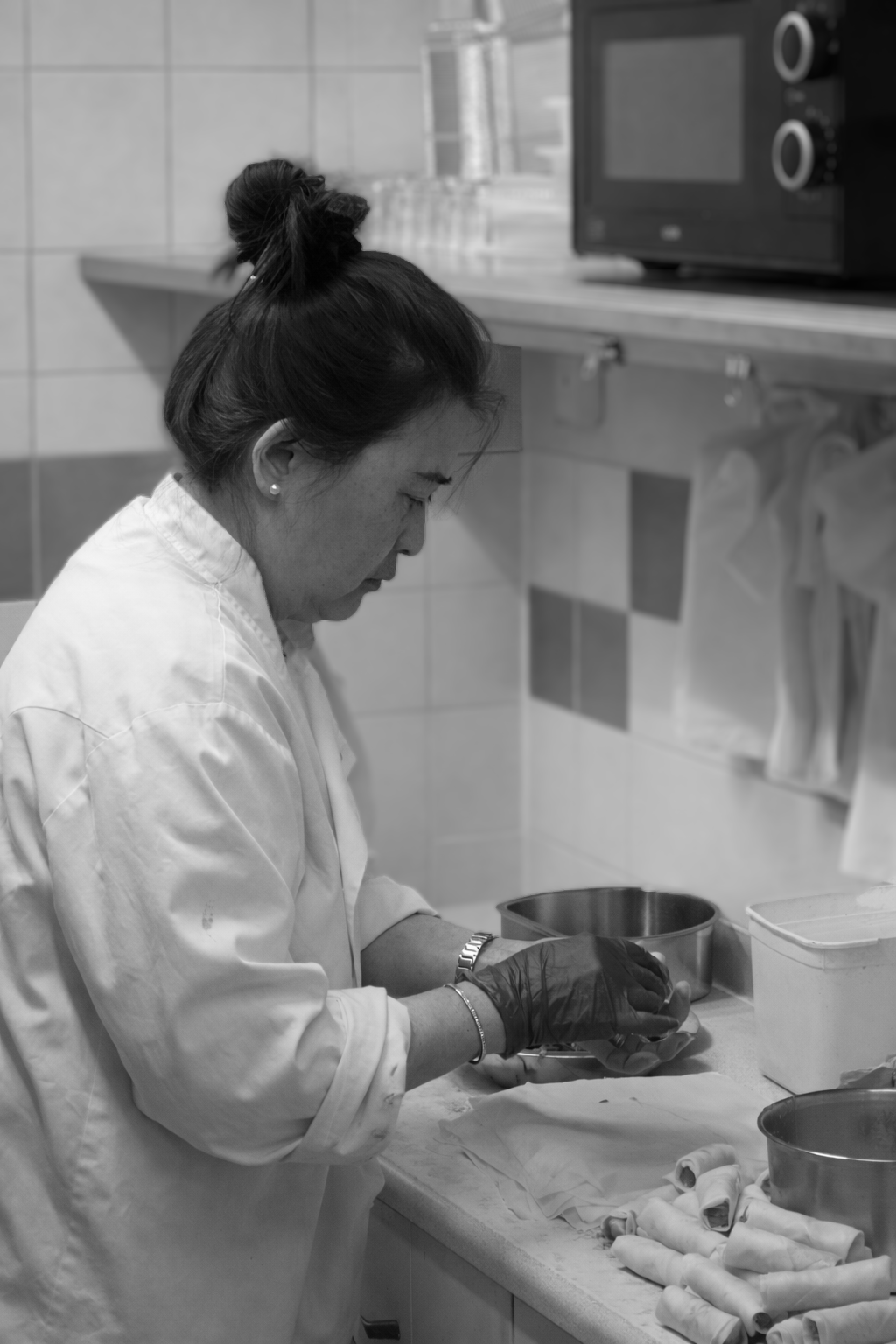 Queenie hand-rolling spring rolls in the kitchen